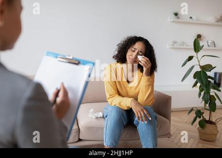 Upset black female consulting psychologist, crying at office, suffering from depression Stock Photo