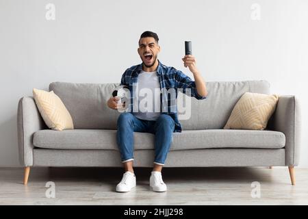 Excited Arab guy spending weekend watching tv celebrating goal Stock Photo