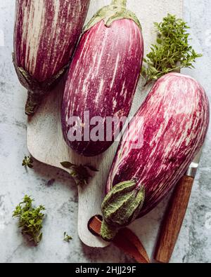 fresch white and purple eggplants and herbs oregano on white wooden board. cooking process. plant base. vegan. healthy food. clean eating. Stock Photo