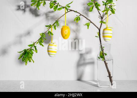 Vase with tree branches decorated with colorful Easter eggs Stock Photo