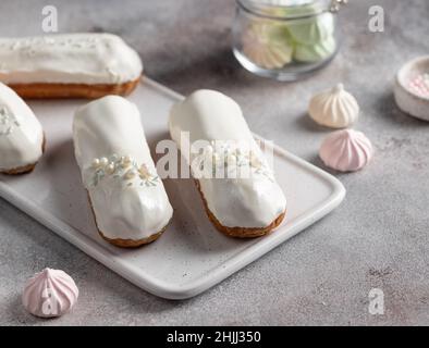 white chocolate glaze eclairs on serving board Stock Photo
