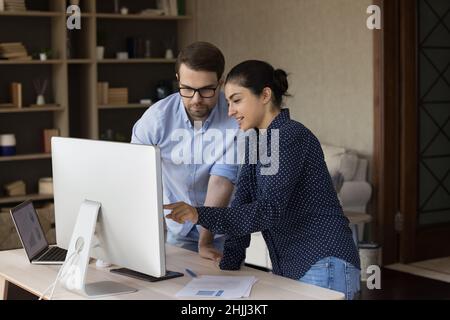 Concentrated smiling young multiracial employees cooperating in office. Stock Photo