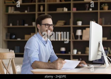 Smiling handsome millennial employee working at home office. Stock Photo