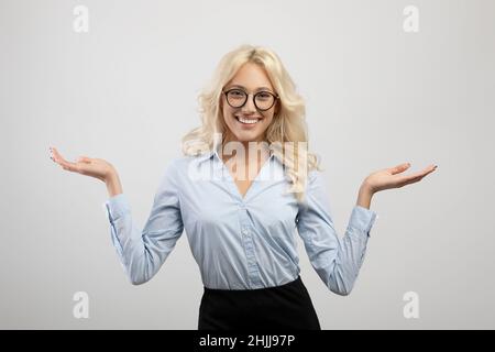 Happy businesswoman comparing options, making scales with her hands, holding invisible objects, light grey background Stock Photo