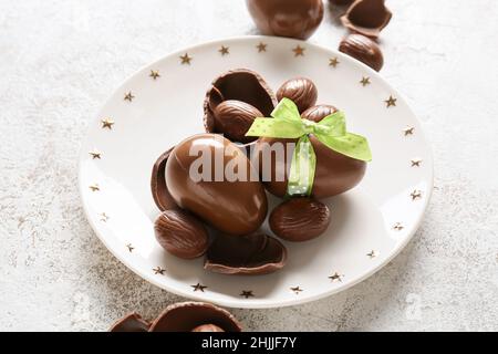 Plate with chocolate Easter eggs on light background Stock Photo
