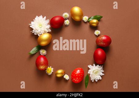 Frame made of stylish Easter eggs and flowers on brown background Stock Photo