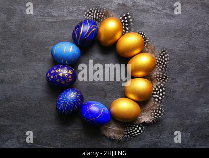 Frame made of stylish Easter eggs and feathers on dark background Stock Photo