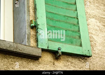 Stone house with green window shutter and shutter holder. Stock Photo