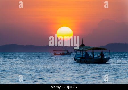 Sunset seen from Ribeira beach in Salvador, Bahia, Brazil. A boat sails at sea. Stock Photo