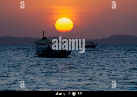 Sunset seen from Ribeira beach in Salvador, Bahia, Brazil. A boat sails at sea. Stock Photo