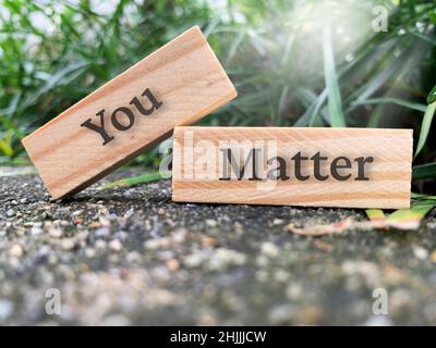 Inspirational and motivational text on wooden block - You matter with plant and shining sun background. Motivational concept. Stock Photo