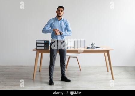 Serious Middle Eastern Male Manager Pointing Finger At Wrist Watch Stock Photo