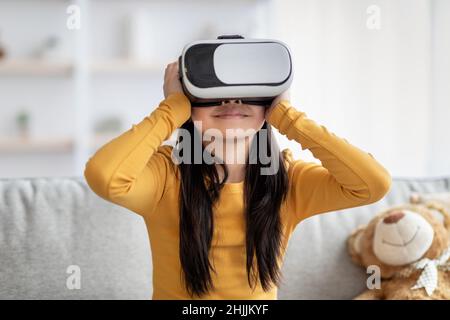 Excited child putting VR glasses on, home interior Stock Photo