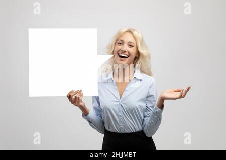 Excited businesswoman holding empty speech bubble, standing over light grey studio background, space for design Stock Photo