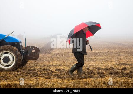 Bandon, Cork, Ireland. 30th January, 2022. John O'Donovan from Clonakilty tries to stay dry from the mist and fog during the West Cork Ploughing Association match on the lands of Derek & Pauline Lovell, Knockbrown, Bandon, Co. Cork, Ireland.  -- Credit; David Creedon / Alamy Live News Stock Photo