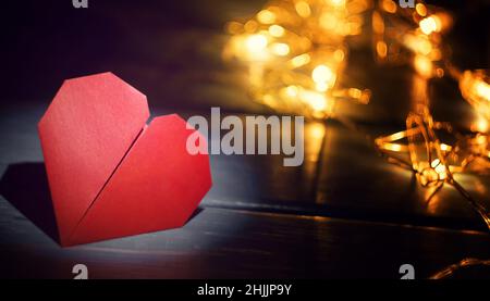 Origami heart on a wooden background with lots of holiday lanterns for Valentine's Day Stock Photo