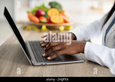 African american female nutritionist working on laptop in office, counting calories or writing diet plan Stock Photo