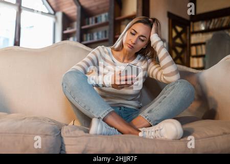 Worried confused lady using cellphone, looking at screen Stock Photo