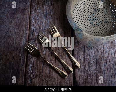 three forks and cutlery on a rustic wooden table Stock Photo