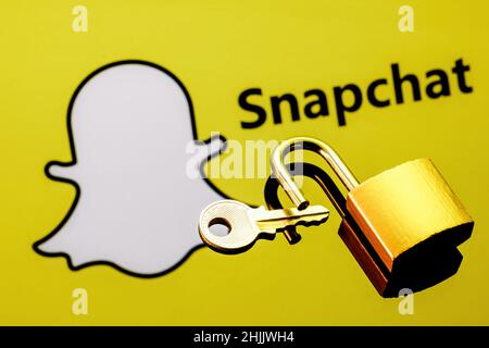 An open security lock and key on the background of the Snapchat instant messaging service logo in the mirror reflection. Stock Photo
