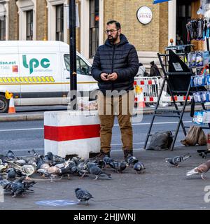 London England UK, 29 January 2022, Man Standing Alone On Pavement Feeding Pigeons London Bridge Southwark Stock Photo