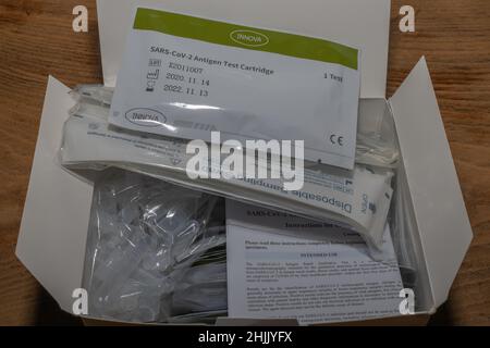 Open box with SARS-CoV-2 antigen test kit showing swabs, cartridges, and leaflet. Labels include CE mark, lot number, and expiry date. Stock Photo