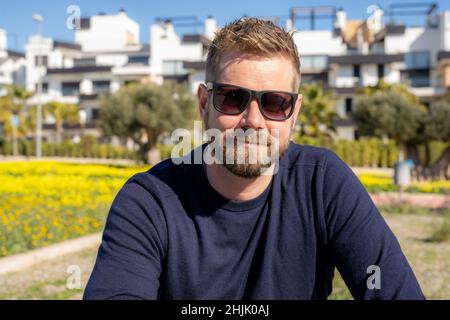 Young bearded man wearing sunglasses smiling happy at the park Stock Photo