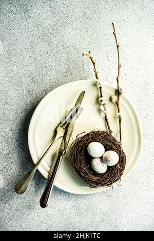 Overhead view of a place setting with Easter eggs in a bird's nest on a table Stock Photo