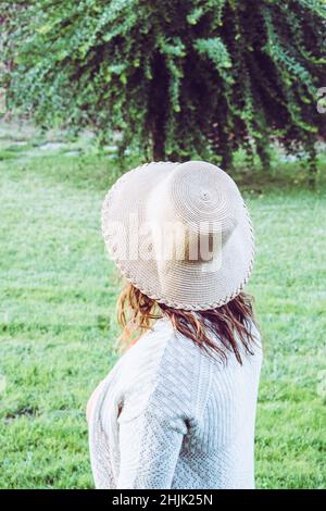 Side view of woman wearing a hat standing in a park, Spain Stock Photo