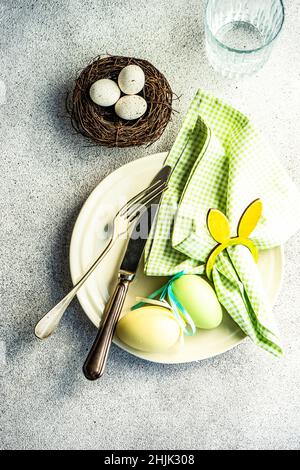 Overhead view of a place setting with Easter eggs in a nest on a table and a glass of water Stock Photo