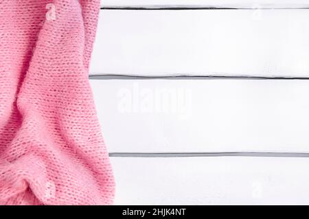 Background with pink knitted blanket on white wooden table, mockup, copy space Stock Photo
