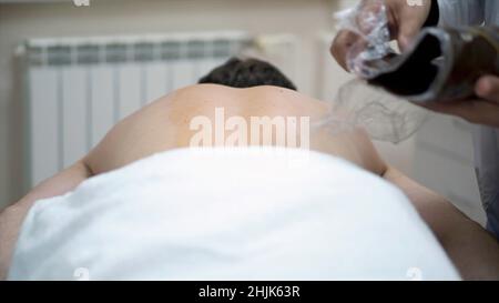 Close-up of man's back during chocolate body wrap treatment. Rest in spa Stock Photo