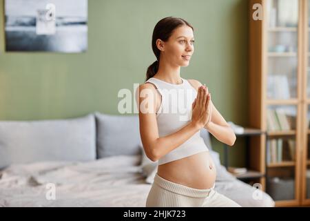Young pregnant woman doing yoga exercises during training in the morning at home Stock Photo