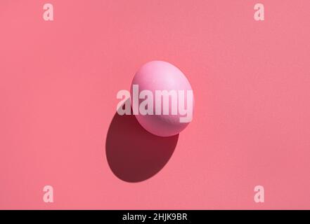 Pink egg on a pink background with a hard shadow. Abstract Easter background. Stock Photo