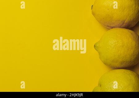 three organic lemons from sicily (siracusa) on a bright yellow paper background with plenty of room for text Stock Photo