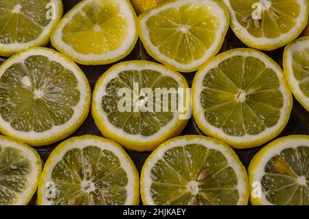 slices of organic Sicilian lemon arranged on a glittered black glass background Stock Photo