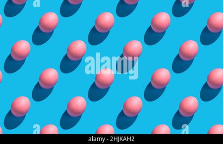The pattern of their pink eggs with a hard shadow on a blue background. Minimalistic abstract Easter background. Stock Photo