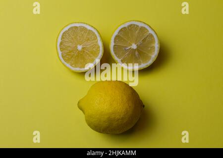 lemon face, two half lemons and a whole lemon which from the arrangement resemble a face, on a background of yellow paper Stock Photo