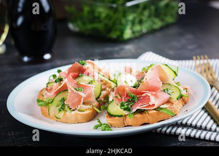 Breakfast or brunch.  Open sandwich with prosciutto or jamon on white plate. Mediterranean appetizer. Stock Photo