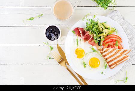English breakfast - fried egg, jamon, toast and fresh vegetables salad. Top view, overhead Stock Photo