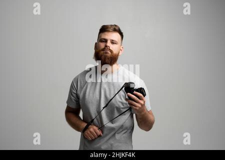 Portrait of handsome and confident bearded man photographer with a professional camera ready for take a picture. Stock Photo