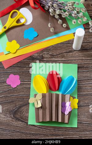 Easter congratulation card with basket easter eggs on wooden table. Handmade. Project of childrens creativity, handicrafts, crafts for kids. Stock Photo