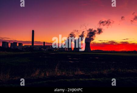 Silhouette of a power station against a winter sunrise near Drax in North Yorkshire, UK, with plumes of water vapour rising from the cooling towers. Stock Photo