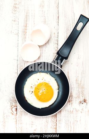 Fried egg in a frying pan on a wooden background. Traditional English breakfast. Food background. Stock Photo