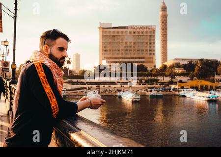 Cairo Egypt December 2021 Man leaning on the fence of a bridge leading to Zamalek area in cairo egypt, cairo tower rising in the distance. Nile river Stock Photo