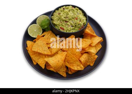 Black plate of guacamole dip and tortilla chips or nachos isolated on a white background Stock Photo
