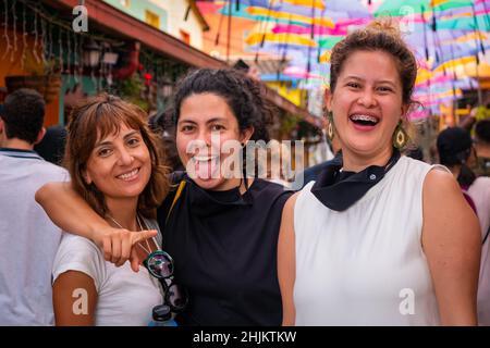 Guatape, Antioquia, Colombia - December 8 2021: Women Friends Pose and Look at the Camera in the Street of Colorful Umbrellas Stock Photo