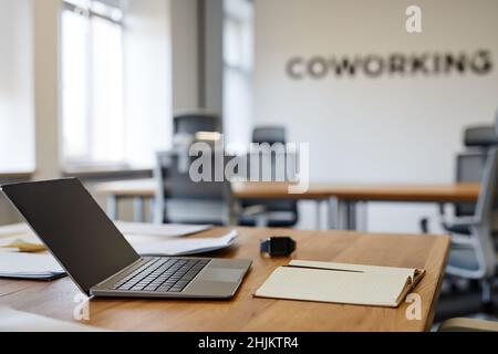 Side view close up of open laptop on desk in empty coworking space, copy space Stock Photo