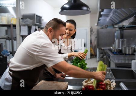 Chefs preparing vegetables for cutting in commercial kitchen. Stock Photo
