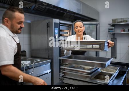 Chef and cook working on their dishes indoors in restaurant kitchen. Stock Photo